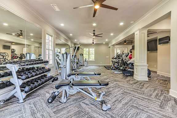 a home gym with cardio equipment and a ceiling fan