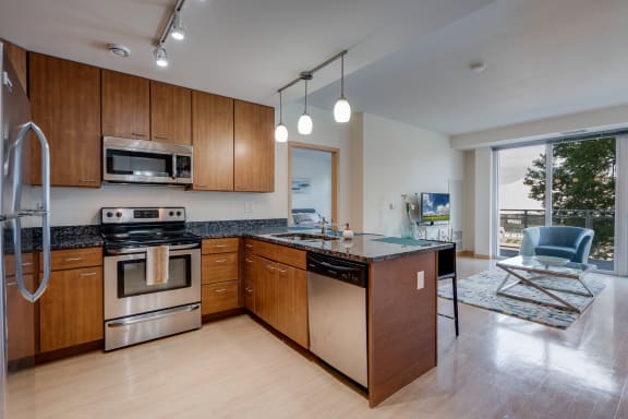 a kitchen with wooden cabinets and stainless steel appliances at Verge Apartments in St. Louis Park, MN