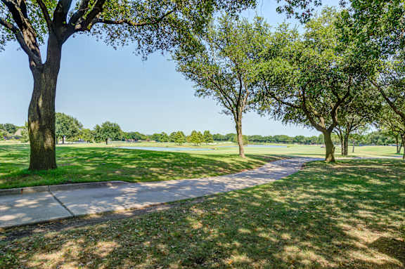 a path through a park with trees and a lake