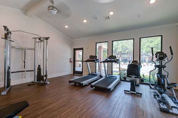 two treadmills and other exercise equipment in a gym with windows