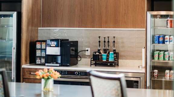 A kitchen with a coffee maker, a refrigerator, and a sink.