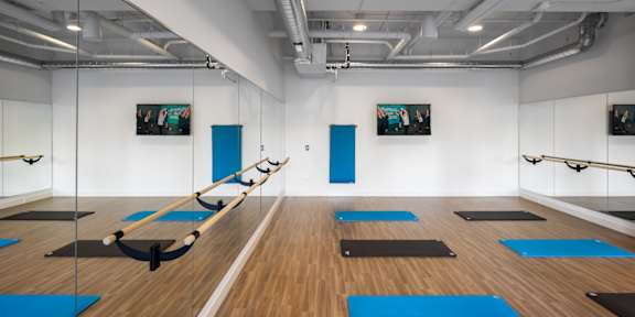 A yoga studio with blue mats and mirrors on the wall.
