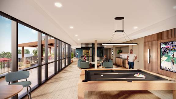 A man is standing in a room with a pool table and a television.