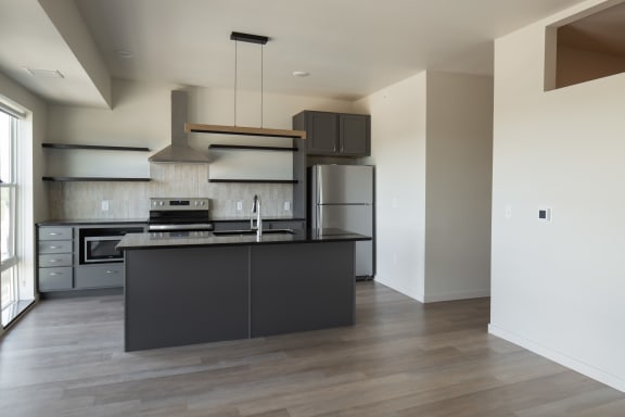 a kitchen with a black island and stainless steel appliances at Riverhouse Apartments, Fargo, ND
