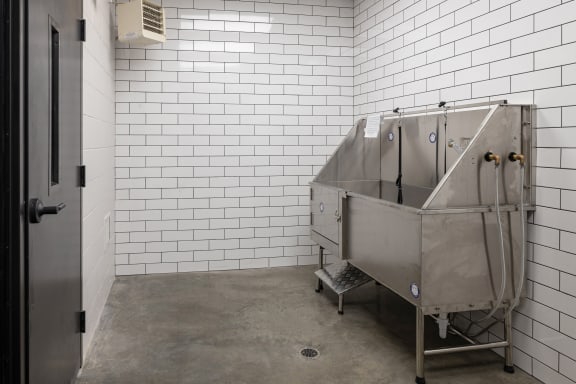 A large metal tub in a white tiled room at Kesler Apartments, Fargo, ND 58102