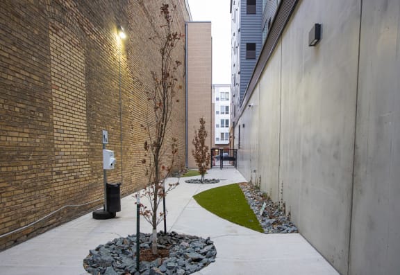 A courtyard with a tree and rocks next to a brick building at Kesler Apartments, Fargo, ND 58102
