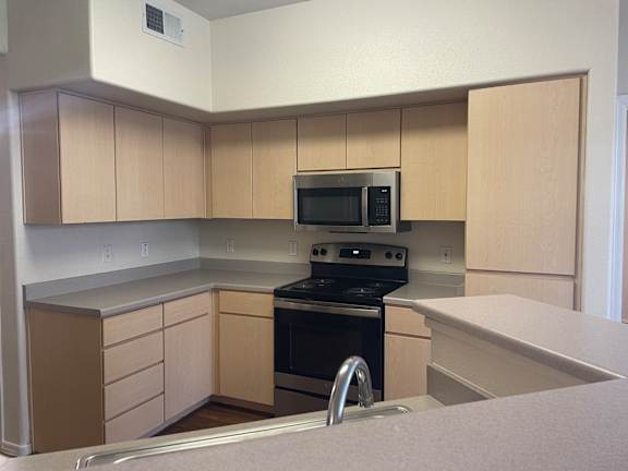 A kitchen with a stove, oven, microwave, and cabinets.