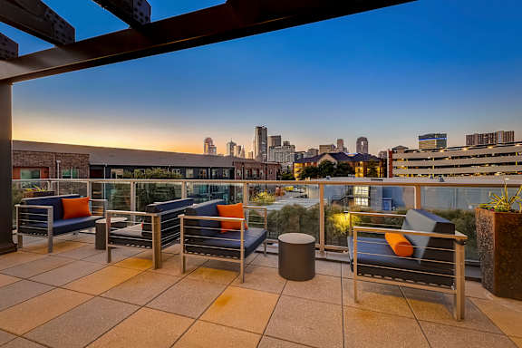 A patio with chairs and a table with a view of the city.