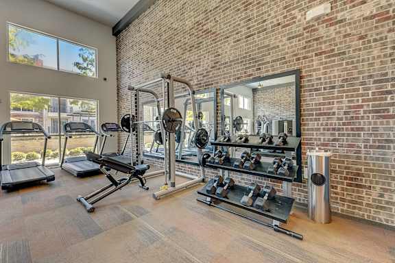 A gym with a brick wall and a variety of equipment.