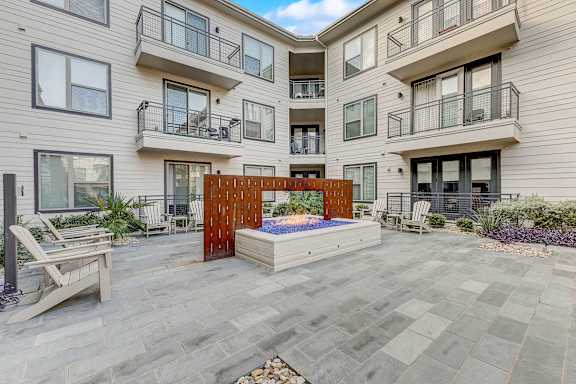 A modern courtyard with a hot tub and chairs.