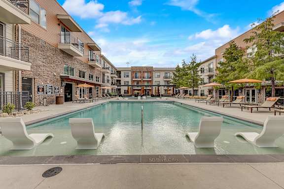 A swimming pool surrounded by white chairs and buildings.