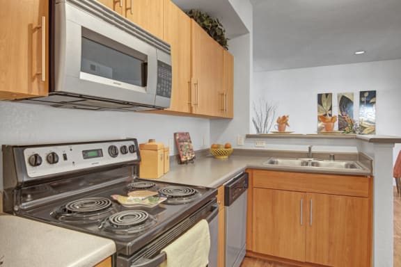 Acclaim Apartments- large kitchen with wooden cabinets and stainless steel appliances