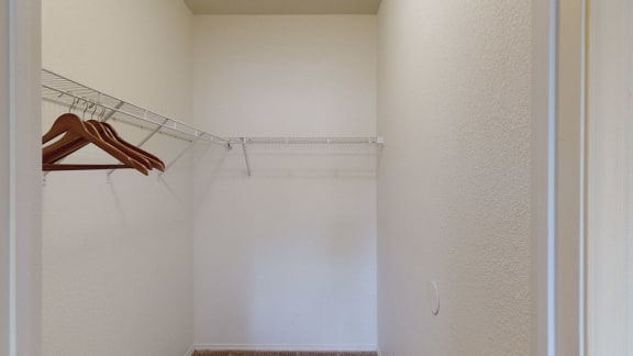 a walk in closet in a bedroom with white walls