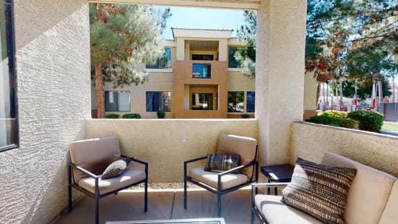 a patio with two chairs and a table in front of a building