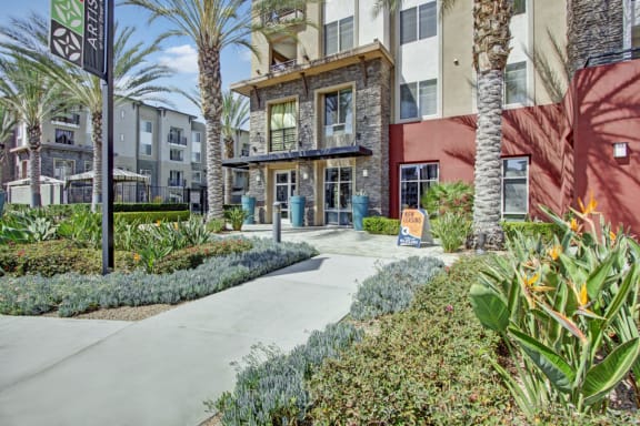 a building with palm trees and a sidewalk in front of it