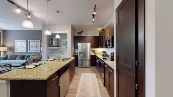 a kitchen with a large island and a living room in the background