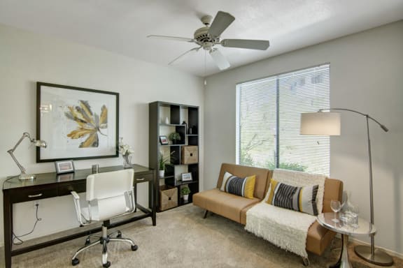 a living room with a couch and a desk with a chair in front of a large window
