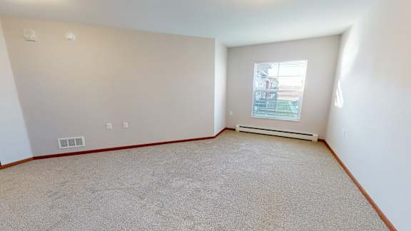 A room with a window and a carpeted floor.