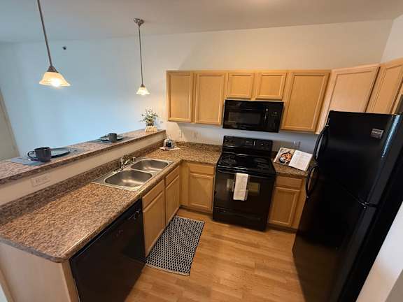 A kitchen with black appliances and wooden cabinets.