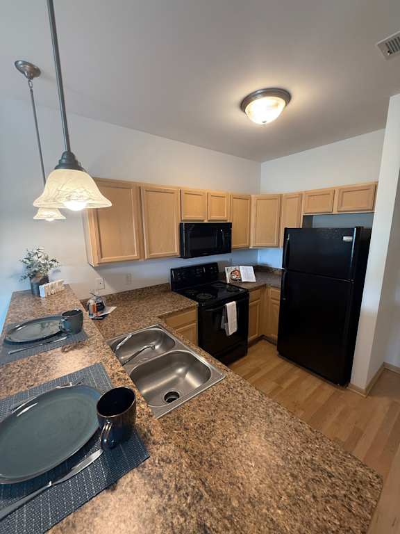 A kitchen with black appliances and wooden cabinets.