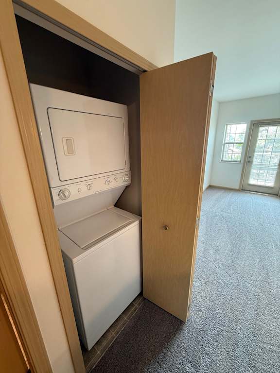 A small white dishwasher is built into a cabinet in a room with a carpeted floor.