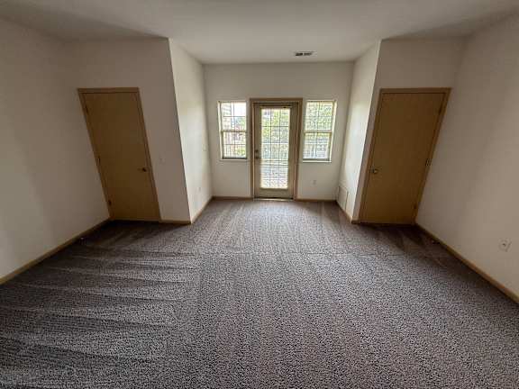 A room with a carpeted floor and three doors.