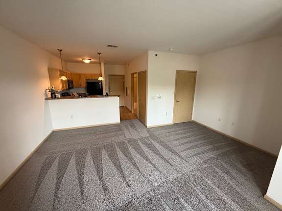 A spacious room with a grey carpet and white walls.