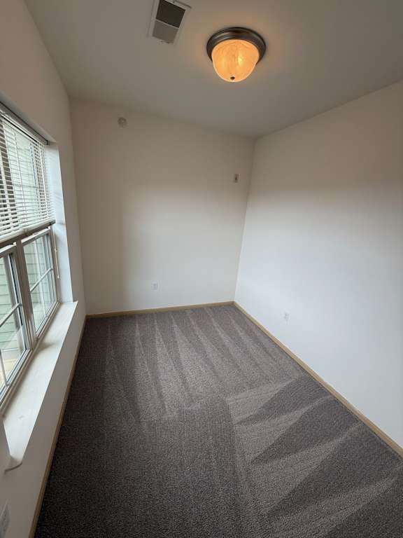 A room with a carpeted floor and a window with blinds.