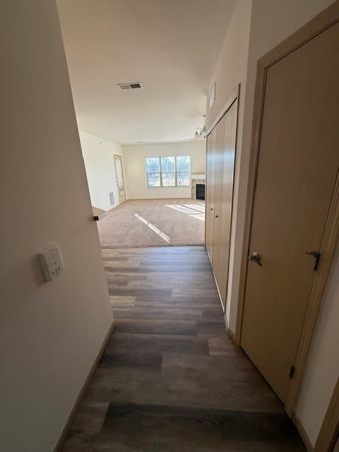A long hallway with a brown floor and white walls.