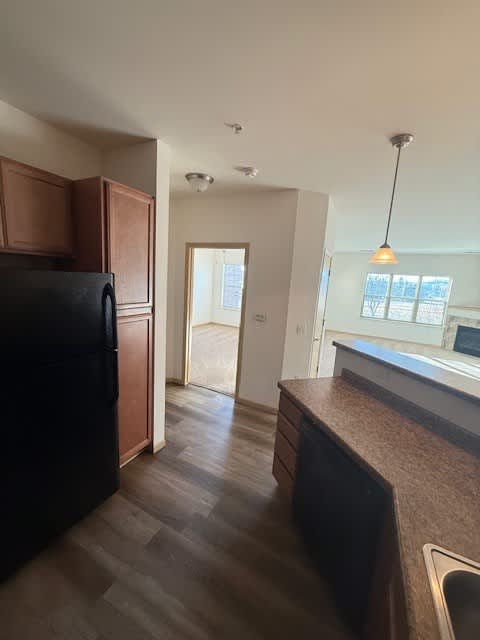 A kitchen with a black fridge and wooden cabinets.