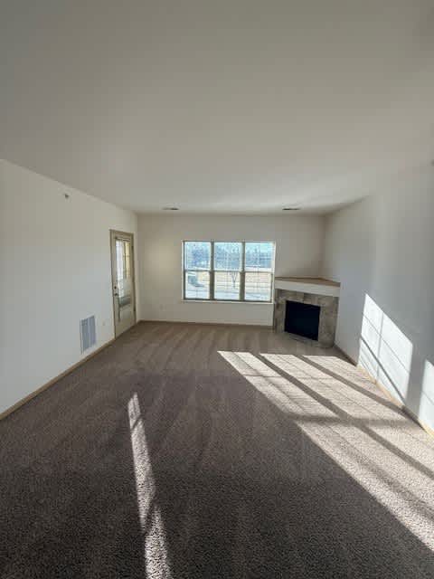 A large empty room with a fireplace and a window.