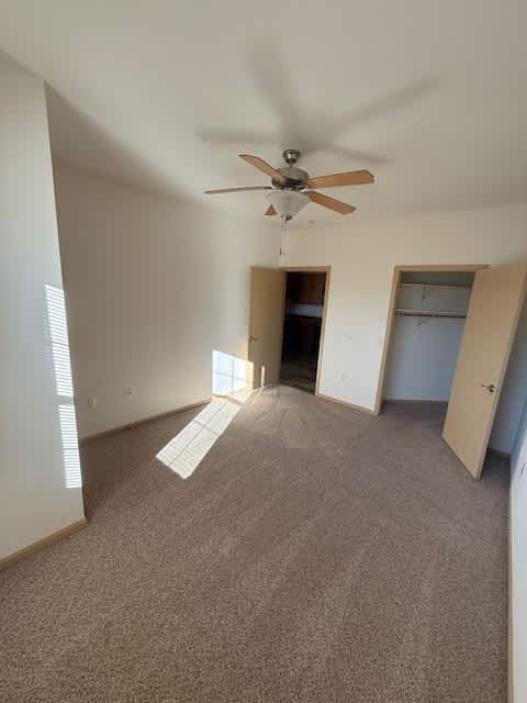 A room with a ceiling fan and carpeted floor.