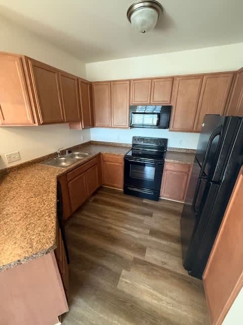 A kitchen with wooden cabinets and a black refrigerator.