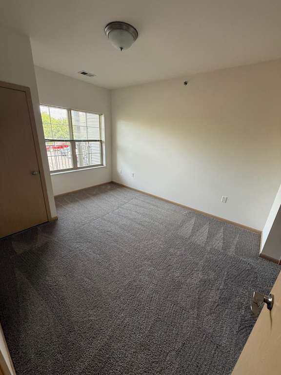 A room with a carpeted floor and a door leading to a balcony.