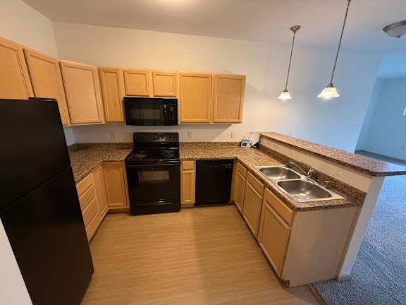 A kitchen with wooden cabinets and black appliances.