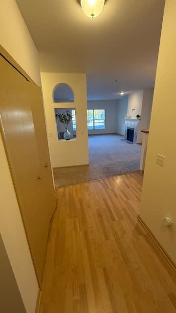 A hallway with wooden floors and a door on the left.