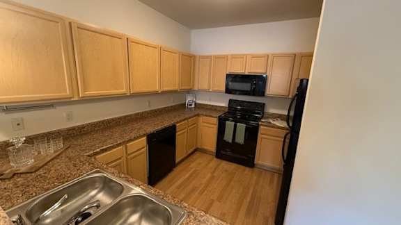 A kitchen with wooden cabinets and black appliances.