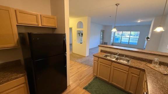 A kitchen with a black fridge and wooden cabinets.
