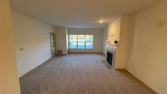 A large, empty room with a fireplace and a window.