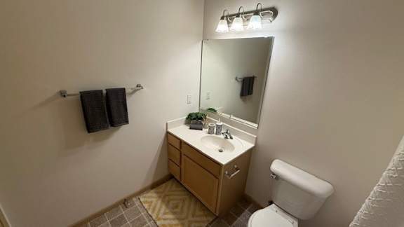 A bathroom with a toilet, sink, mirror, and towel rack.