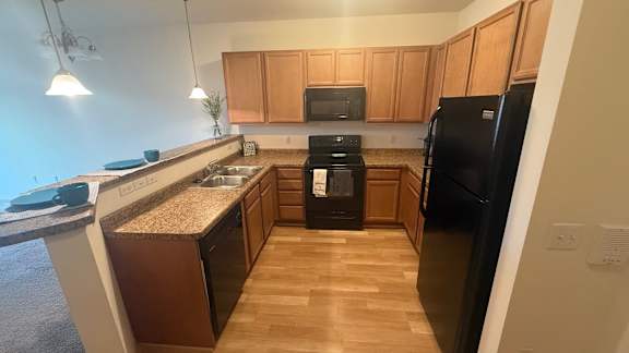 A kitchen with wooden cabinets and black appliances.