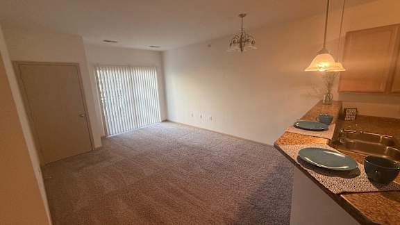 A kitchen area with a sink, counter, and a window with blinds.