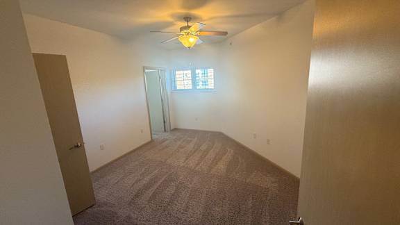 A room with a ceiling fan and carpeted floor.