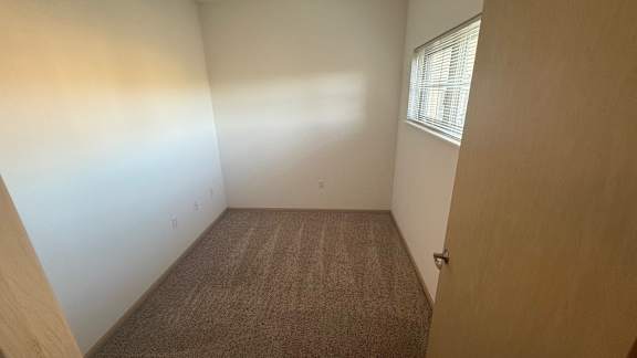 A room with a carpeted floor and a door on the right side.