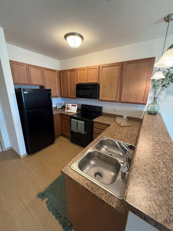 A kitchen with a black refrigerator and a black stove.