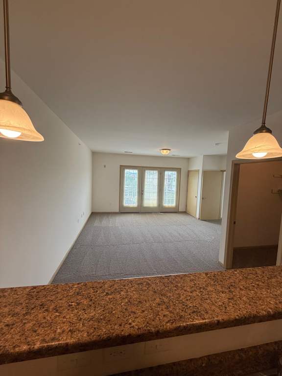 A room with a brown granite counter in the foreground and a window with blinds in the background.