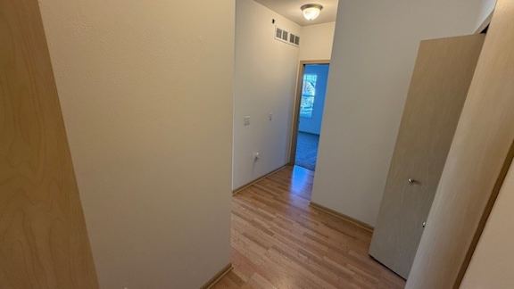 A hallway with a wooden floor and a door at the end.