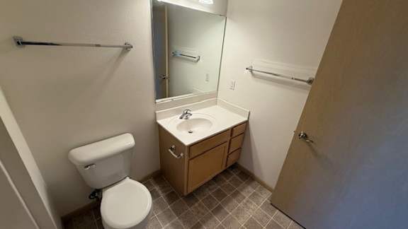 A bathroom with a toilet, sink, and mirror.