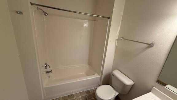 A white toilet sits next to a bathtub in a bathroom.