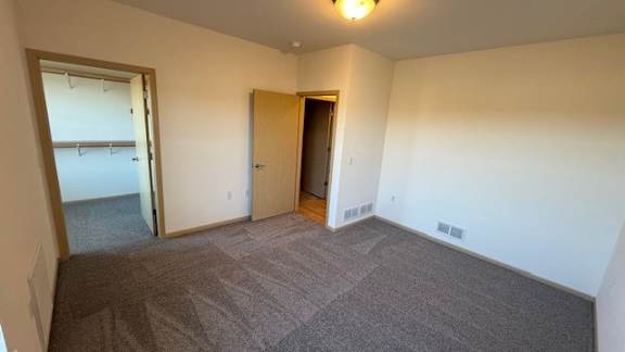 A carpeted room with a door and a window.